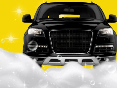 Black car against a Rocket Express Car Wash brand yellow background surrounded by suds